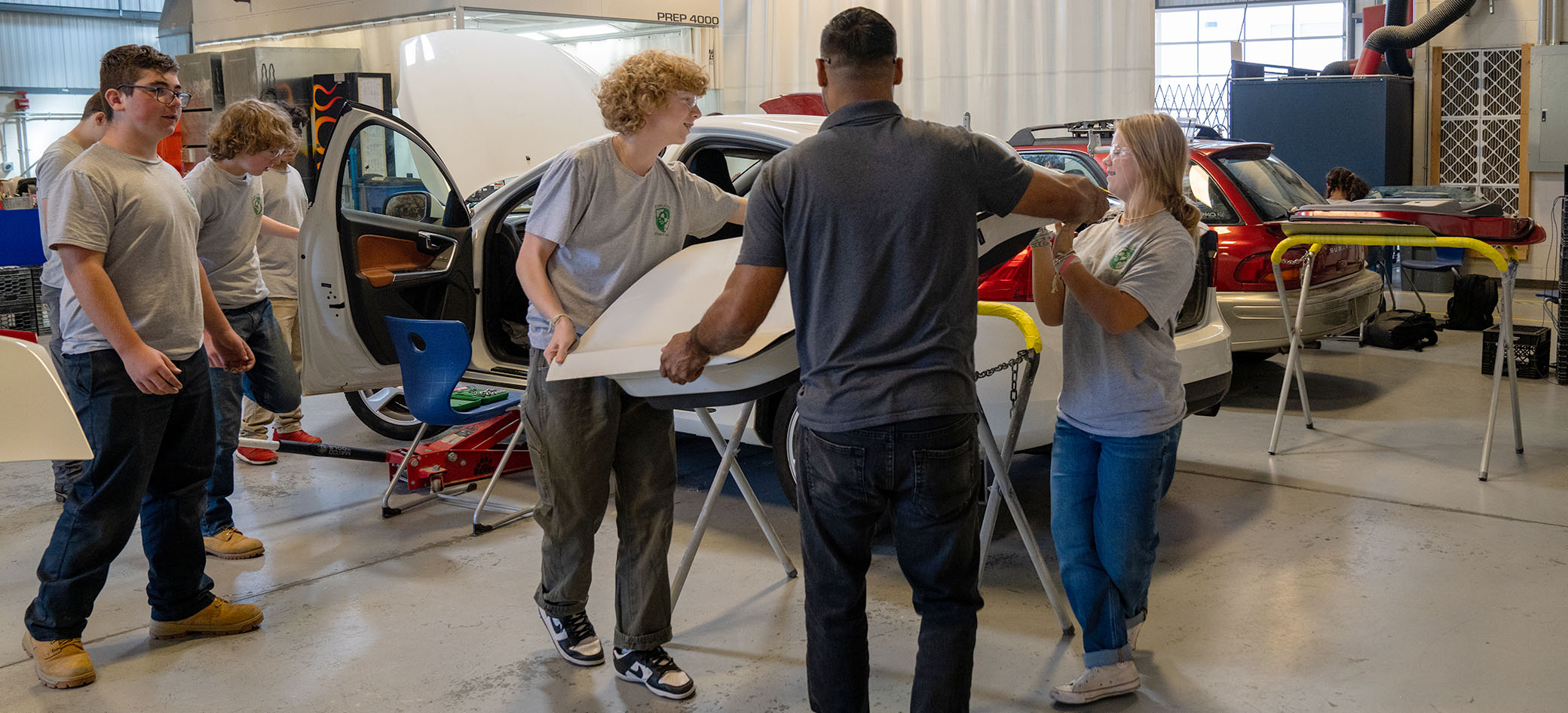 Students and a teacher carry a car door.