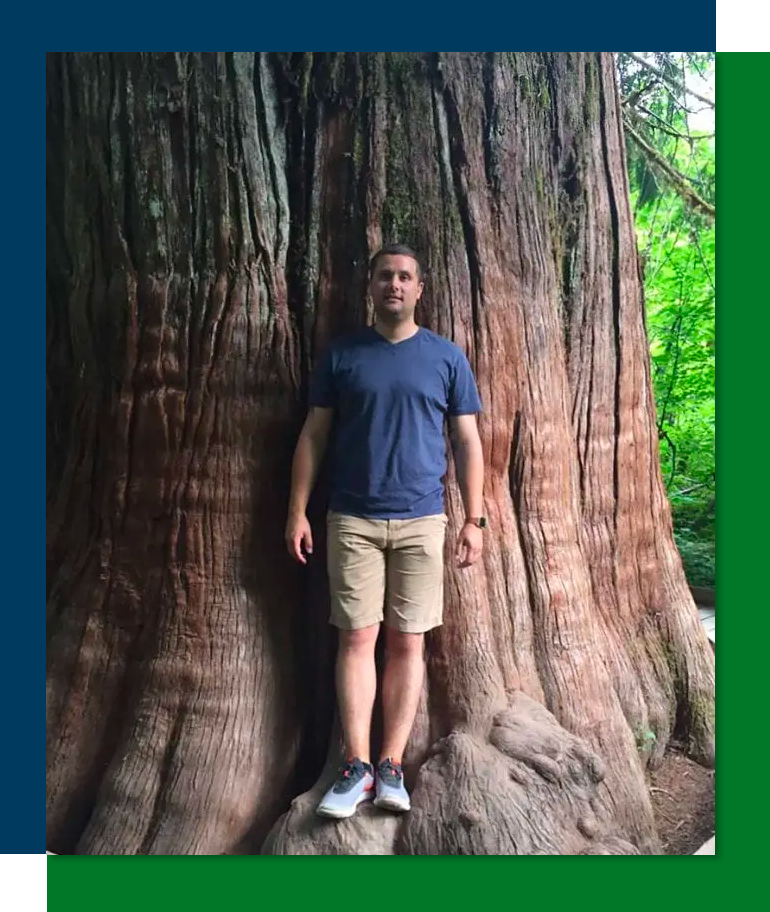 Jake Maynard Class Of 2008 leaning back against the trunk of a very large tree.