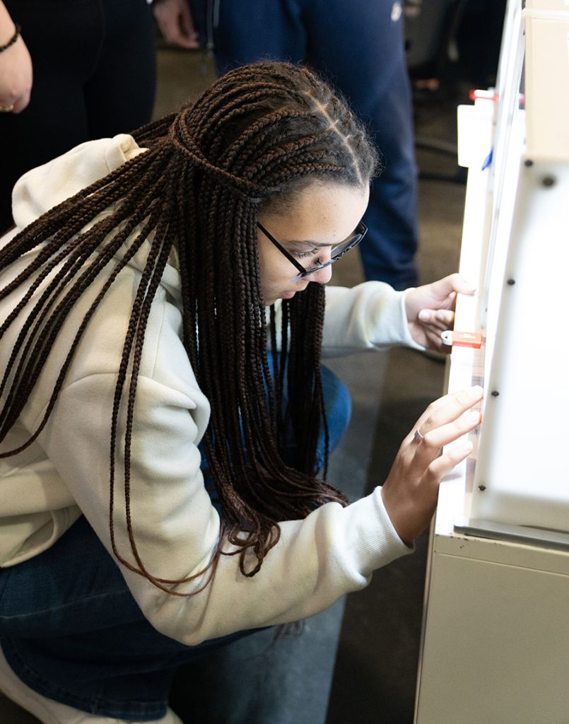 A student enters information into a 3D printer.