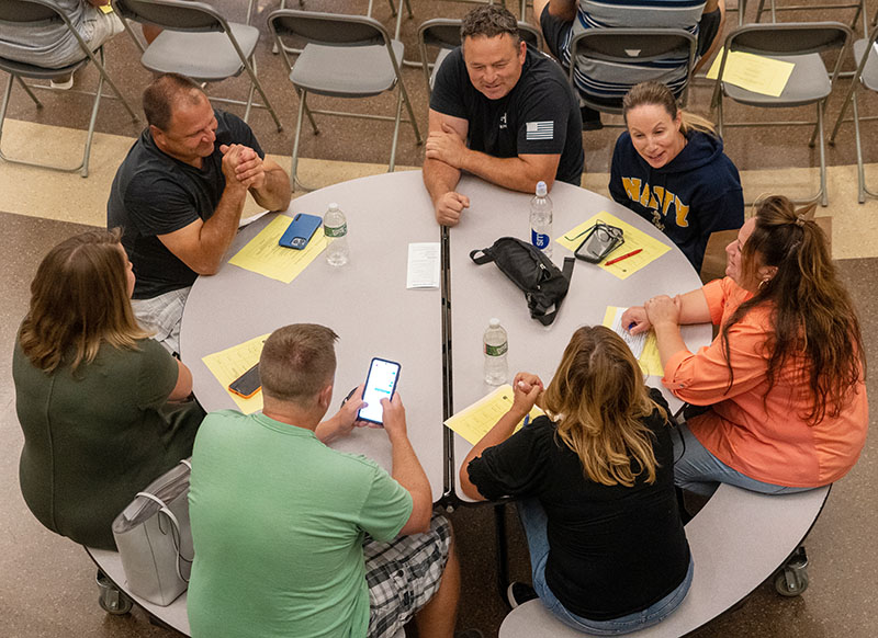 Parents sit and talk around a round table.