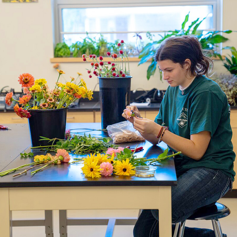 A student works with fresh cut flowers.